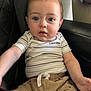 baby, child, infant, calvin_klein, striped_shirt, beige_shorts, leather_chair, blue_eyes, short_hair, mohawk, cute, sitting, indoor, curious, person, apparel, casual_clothing, closeup, portrait, young