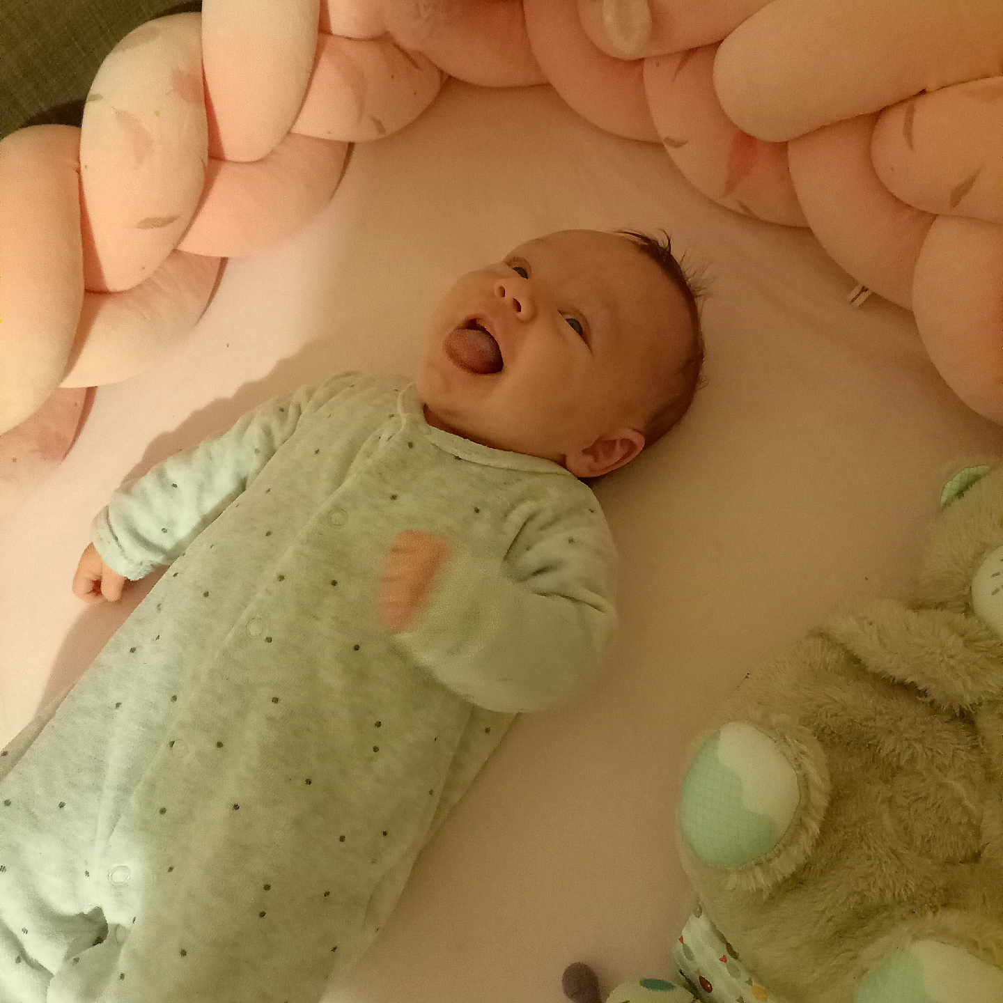 Joy a rejoint le concours — aidez-le/la à gagner de superbes lots ! baby, bedroom, braided_cushion, child, cozy, crib, cute, happy, indoor, infant, lying_down, onesie, pink, playful, plush_toy, sleepwear, smiling, soft_toy, toddler, tongue_out