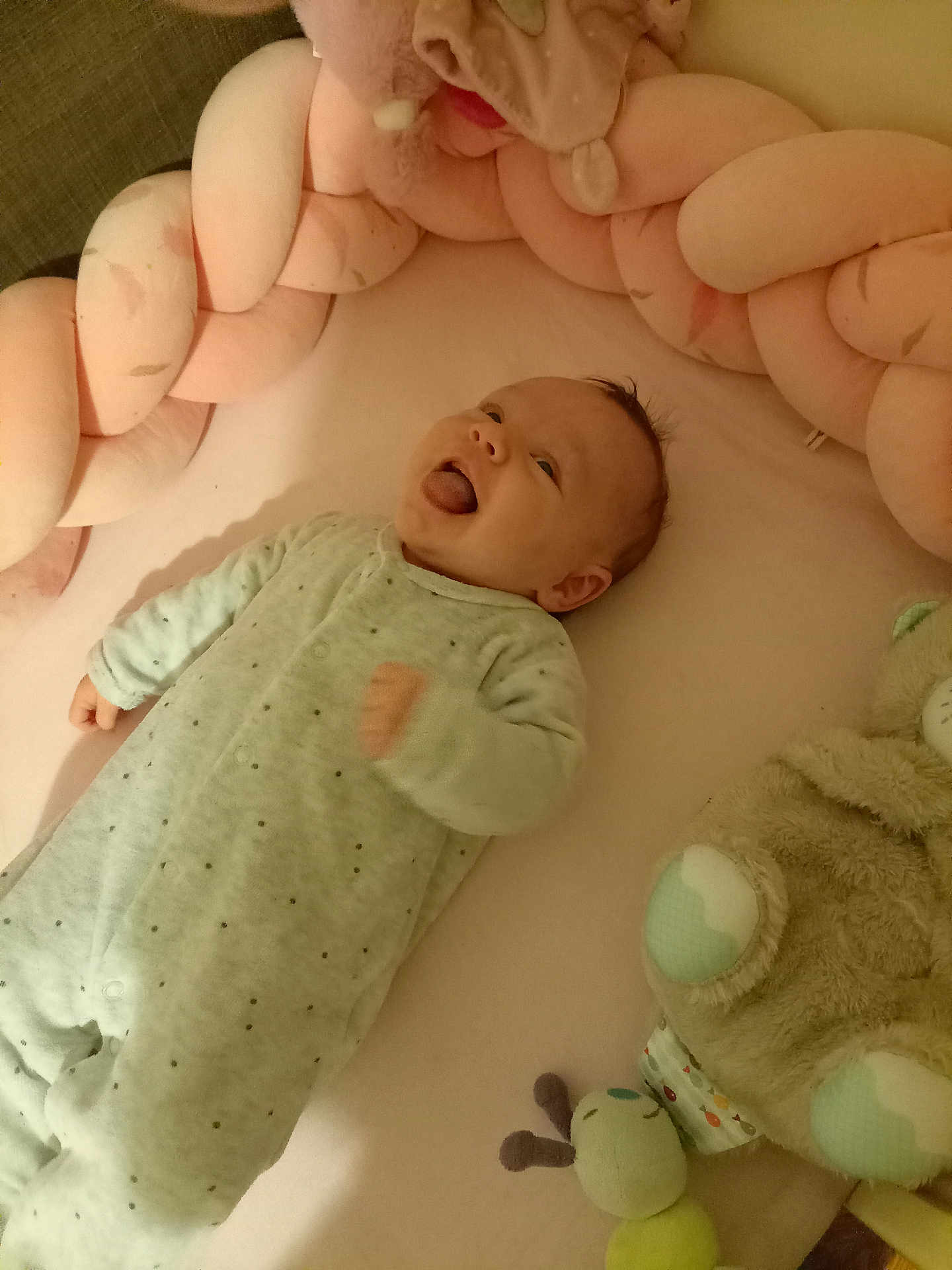 Joy a rejoint le concours — aidez-le/la à gagner de superbes lots ! baby, infant, onesie, plush_toy, soft_toy, braided_cushion, crib, smiling, tongue_out, cute, child, sleepwear, pink, bedroom, cozy, lying_down, playful, happy, indoor, toddler