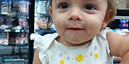 Sally joined the competition — help win amazing prizes! toddler, child, shopping_cart, bow, toy, grocery_store, freezer, clothing, earrings, white_shirt, closeup, face, cute, curious, indoor, person, baby, small_child, smile, playful