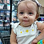 toddler, child, shopping_cart, bow, toy, grocery_store, freezer, clothing, earrings, white_shirt, closeup, face, cute, curious, indoor, person, baby, small_child, smile, playful