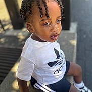 Kenzo participe au concours pour gagner de l'argent avec cette photo : toddler, child, braided_hair, white_tshirt, shorts, sneakers, outdoor, bench, sunlight, shadow, side_view, casual_clothing, portrait, young_child, curious, daylight, street, fashion, person, sitting