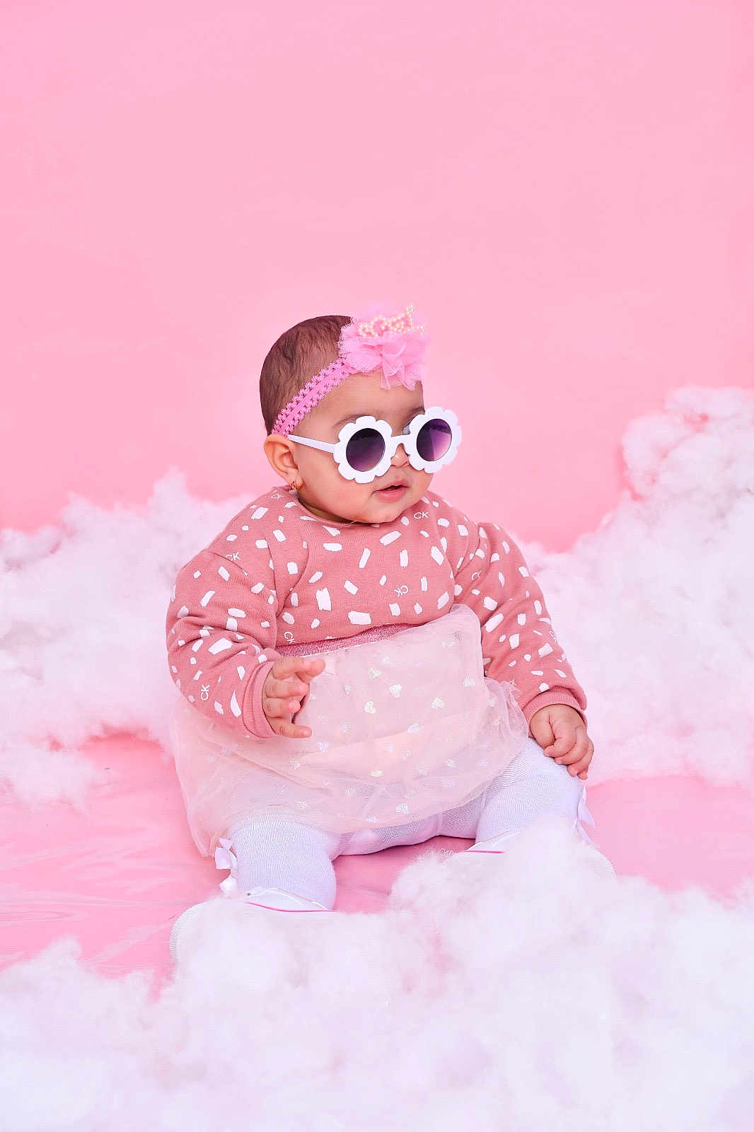 Eline a rejoint le concours — aidez-le/la à gagner de superbes lots ! baby, child, pink_background, sunglasses, headband, flower_glasses, tulle_skirt, patterned_sweater, white_tights, sitting, fluffy_clouds, studio_photo, cute, fashion, portrait, indoor, adorable, smiling, infant, soft_texture