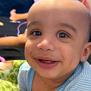 Derek joined the competition — help win amazing prizes! baby, child, infant, smiling, happy, portrait, close_up, face, eyes, teeth, blue_shirt, striped_clothing, indoor, blanket, cozy, seated, family, playful, camera, candid