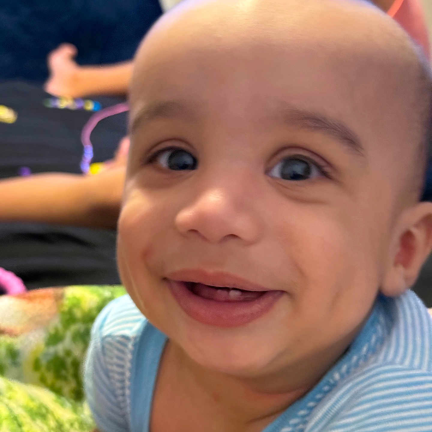 Derek joined the competition — help win amazing prizes! baby, child, infant, smiling, happy, portrait, close_up, face, eyes, teeth, blue_shirt, striped_clothing, indoor, blanket, cozy, seated, family, playful, camera, candid