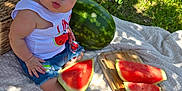 Makayla joined the competition — help win amazing prizes! baby, child, watermelon, bow, outdoor, picnic, blanket, grass, tree, fruit, summer, cute, jeans, sleeveless_shirt, shadows, sunlight, basket, food, sitting, nature