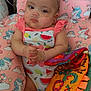 baby, infant, pink_bows, fruit_pattern, unicorn_cushion, colorful_book, cute, child, lying_down, soft_toy, indoors, clothing, headwear, face, hand, toy, fabric, pattern, comfort, resting