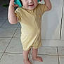 barefoot, blue_eyes, cabinet, child, cute, happy, headphones, home, indoor, kitchen, person, playful, short_hair, smiling, standing, tile_floor, toddler, toilet, yellow_onesie, young_child