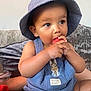 toddler, child, baby, blue_hat, peter_rabbit, overalls, watermelon, fruit, eating, couch, indoor, cute, hands, face, eyes, skin, clothing, sitting, relaxed, soft_furniture