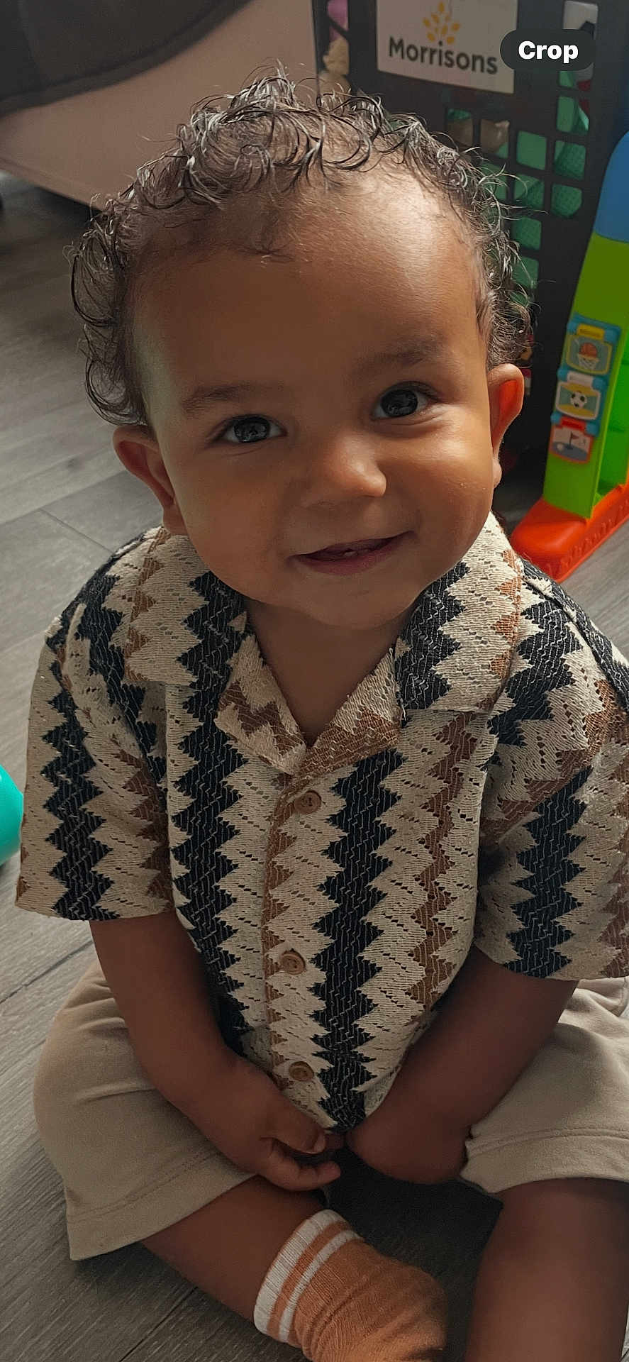Huxley joined the competition — help win amazing prizes! toddler, child, smiling, curly_hair, indoor, floor, patterned_shirt, beige_shorts, sitting, toy, play, cute, happy, person, young_child, casual_clothing, sock, home, portrait, baby