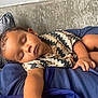 Huxley is registered to the contest to win money with this photo: toddler, sleeping, child, sofa, cushion, curly_hair, patterned_shirt, indoor, relaxation, peaceful, face, hand, skin, earring, home, comfort, rest, portrait, person, casual