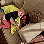 black_shirt, blanket, bottle, child, clothing, couch, cozy, floor, hair, indoor, kids, living_room, person, pink_pants, playful, resting, smiling, texture, wooden_floor, young_child