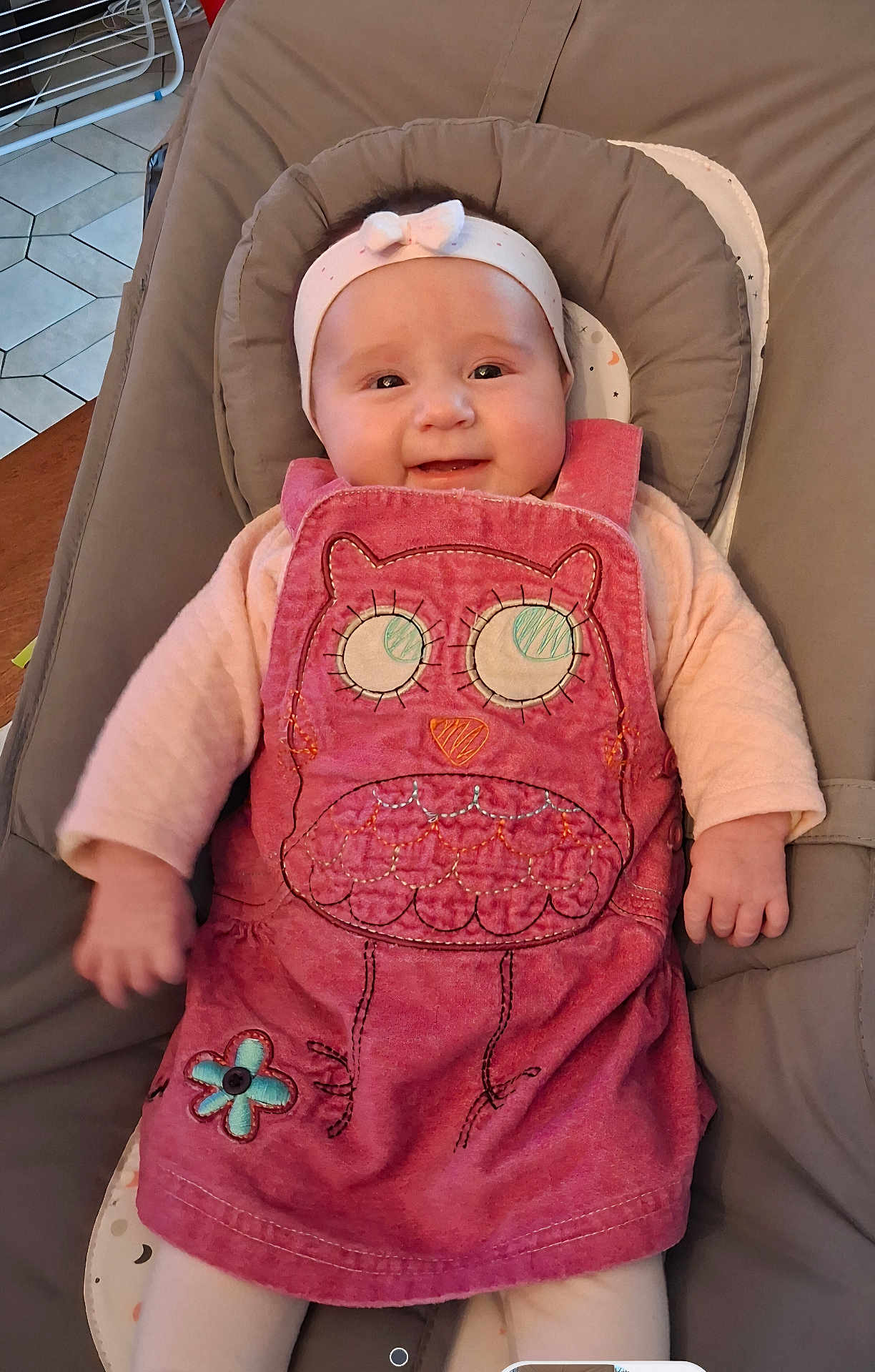 Kalyana a rejoint le concours — aidez-le/la à gagner de superbes lots ! baby, infant, smiling, headband, bow, pink_dress, owl_applique, bouncer_seat, cushion, indoor, tile_floor, table_edge, arm, hand, white_tights, portrait, cute, cozy, clothing, baby_seat