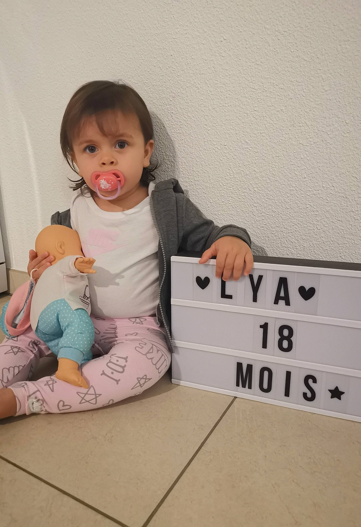 Lya participe au concours pour gagner de l'argent avec cette photo : baby, baby_toddler_clothing, barefoot, child, comfort, flooring, font, foot, happy, knee, person, photo_caption, play, room, sitting, sleeve, sock, t_shirt, thigh, toddler