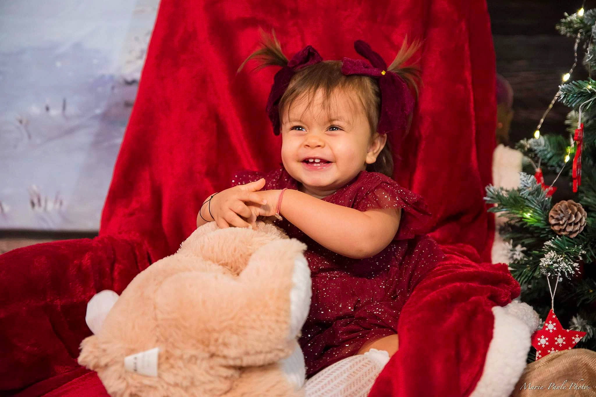 Lya participe au concours pour gagner de l'argent avec cette photo : baby, baby_toddler_clothing, cheek, child, christmas_tree, dress, eye, fun, happy, head, human_body, iris, joy, person, pink, red, skin, sleeve, smile, standing