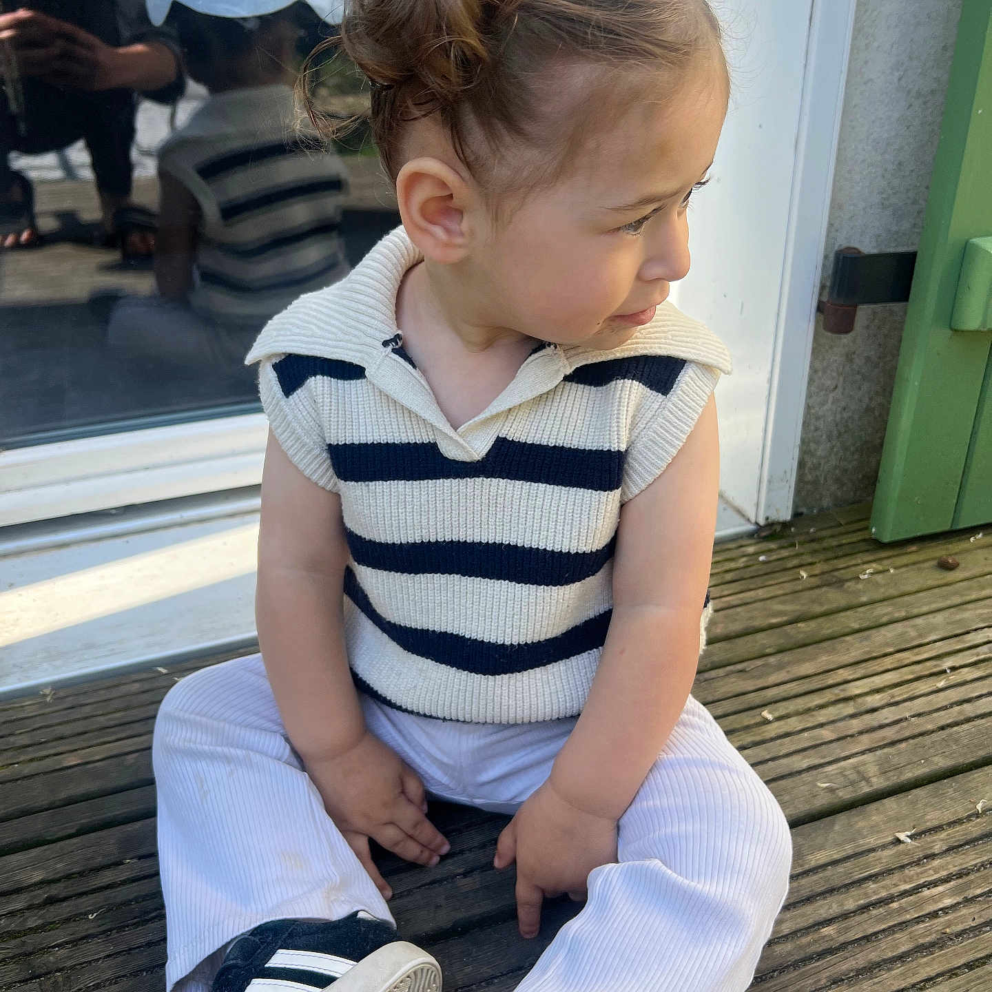 Talya participe au concours pour gagner de l'argent avec cette photo : casual_clothing, child, curious_expression, curly_hair, cute, daylight, fashion, glass_door, outdoor, person, portrait, reflection, side_view, sitting, sneakers, striped_sweater, toddler, white_pants, wooden_deck, young_child