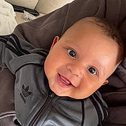 Idrys a rejoint le concours — aidez-le/la à gagner de superbes lots ! baby, child, smile, face, eyes, jacket, clothing, hand, person, indoor, couch, fabric, happy, cute, portrait, closeup, adorable, young, sitting, holding