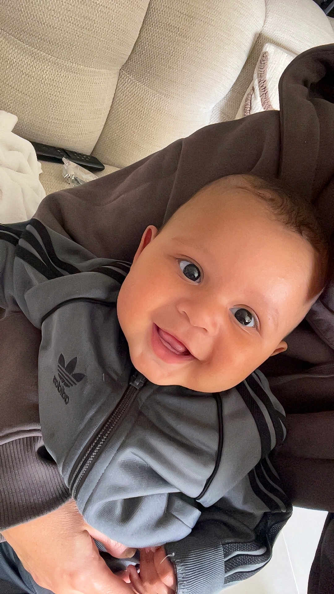 Idrys a rejoint le concours — aidez-le/la à gagner de superbes lots ! baby, child, smile, face, eyes, jacket, clothing, hand, person, indoor, couch, fabric, happy, cute, portrait, closeup, adorable, young, sitting, holding