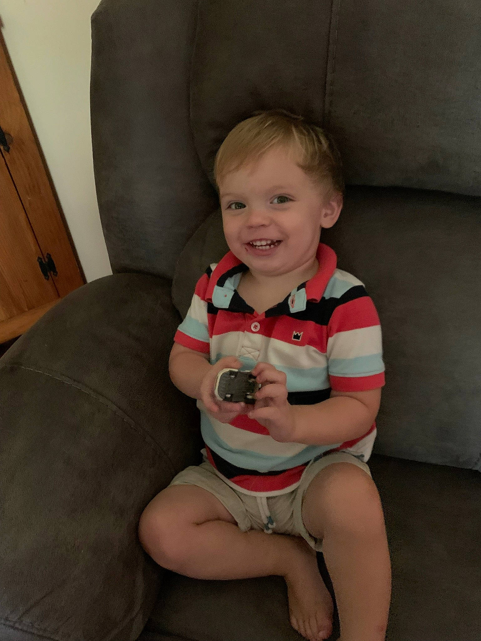 Riley is registered to the contest to win money with this photo: arm, baby_toddler_clothing, chair, cheek, chin, comfort, eye, finger, furniture, happy, human_body, iris, joy, knee, lap, leg, person, skin, smile, thigh