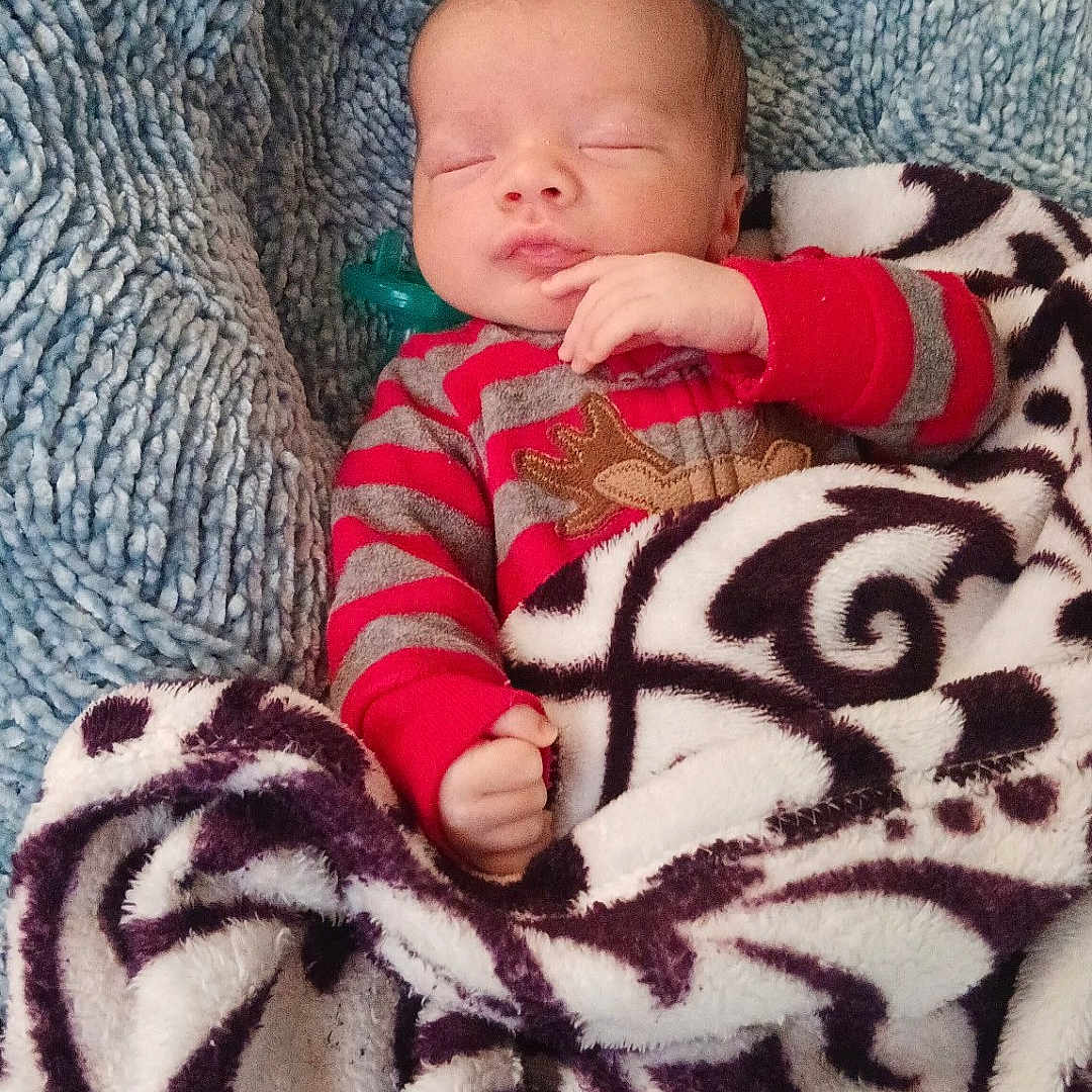 Tru'Amor joined the competition — help win amazing prizes! baby, blanket, child, cozy, cute, face, hand_near_face, head, indoors, infant, newborn, peaceful, portrait, red_striped_clothing, reindeer_design, resting, sleeping, soft_texture, warm, wrapped