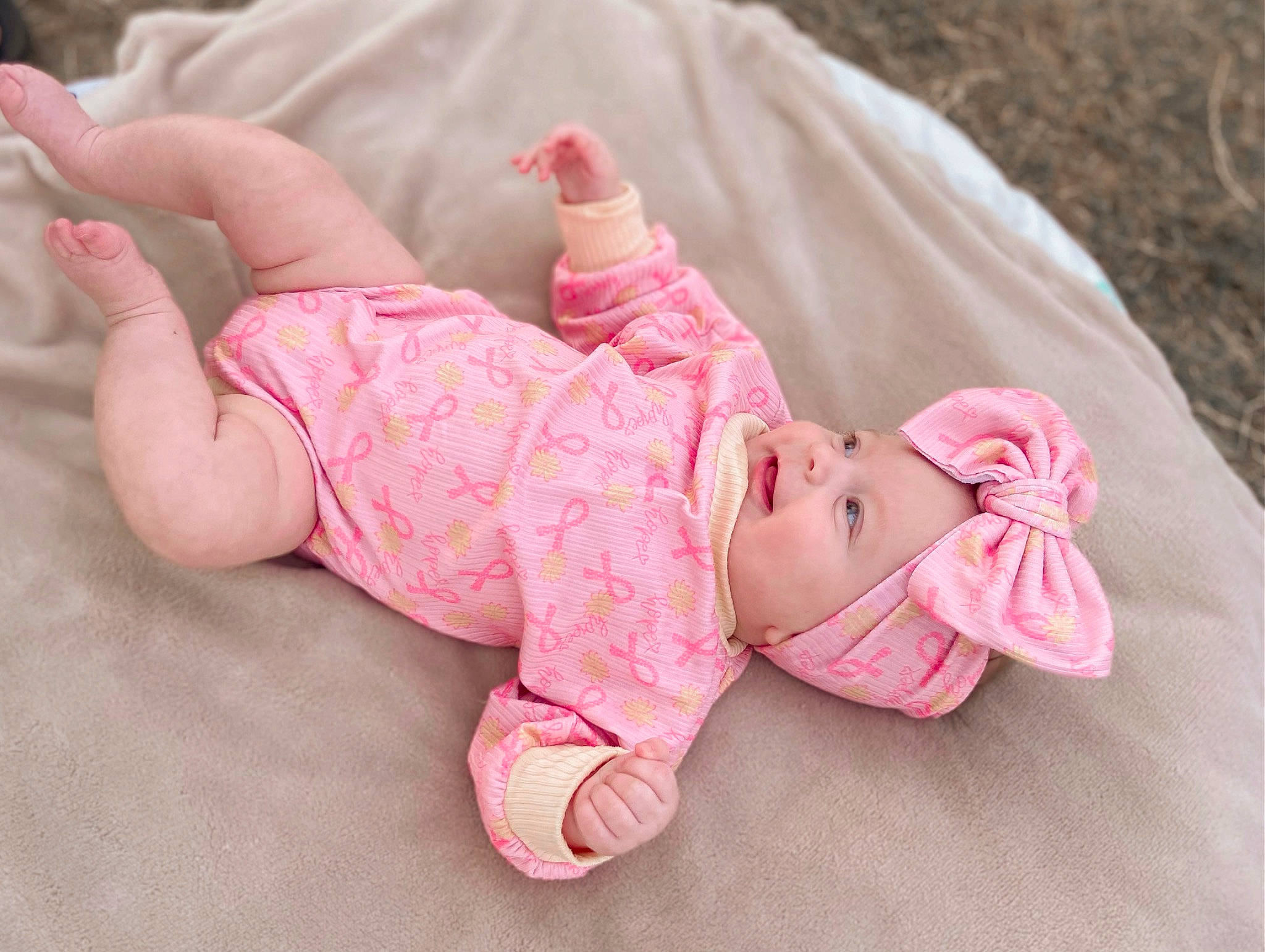 Kinzley is registered to the contest to win money with this photo: baby, baby_products, baby_toddler_clothing, barefoot, cheek, child, comfort, eye, flooring, foot, grass, headwear, human_leg, linens, pattern, person, pink, sitting, skin, sleeve