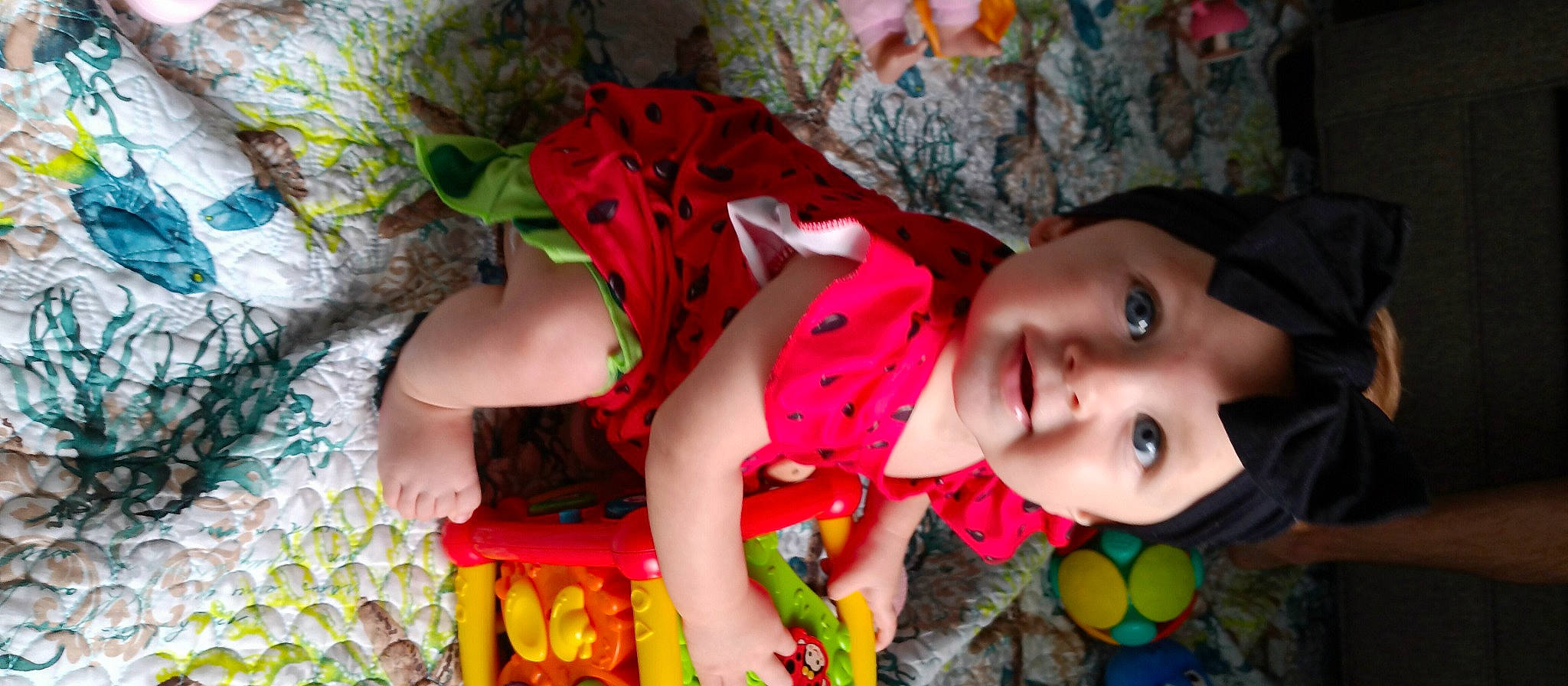 Caroline is registered to the contest to win money with this photo: baby, baby_toddler_clothing, cheek, child, fun, green, happy, human, human_body, lip, mouth, organism, pattern, person, pink, plant, red, textile, toddler, tree