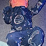newborn, baby, infant, sleeping, onesie, space_theme, planets, stars, blue_clothing, cozy, blanket, soft_surface, cute, peaceful, portrait, indoor, child, young, resting, human