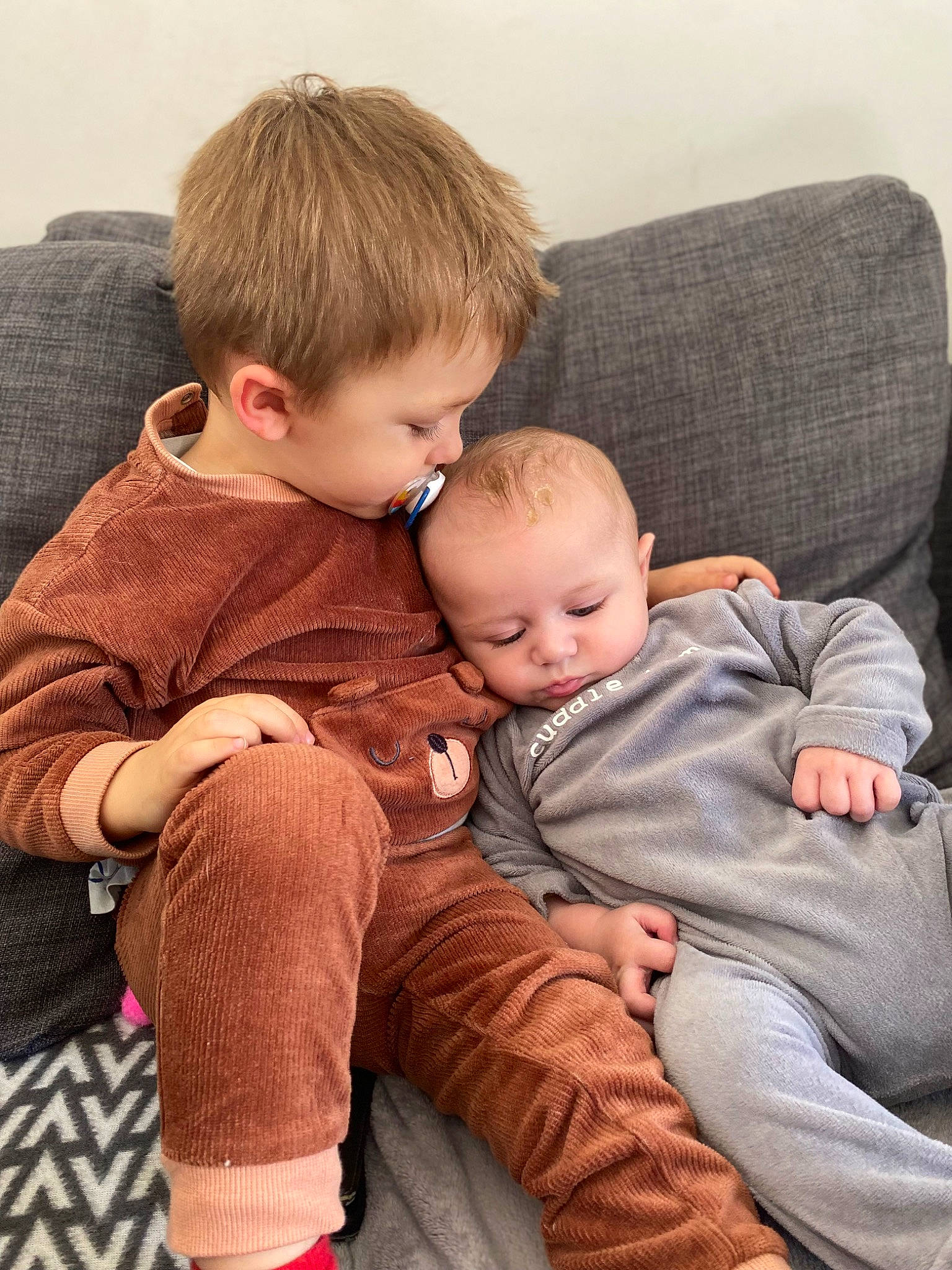 Louis a rejoint le concours — aidez-le/la à gagner de superbes lots ! baby, baby_toddler_clothing, cheek, child, comfort, couch, flooring, foot, fur, interaction, lap, leg, person, room, sibling, sitting, skin, sleeve, thigh, toddler