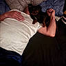person, dog, bed, pillow, white_shirt, black_brown_dog, arm, hand, resting, indoor, casual, relaxation, pet, companion, blanket, fabric, human, animal, cute, comfort