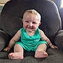baby, child, smiling, blue_eyes, armchair, green_clothing, barefoot, indoors, cute, happy, portrait, sitting, plush_furniture, infant, young_child, face, skin, person, room, light