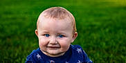 Anthony is registered to the contest to win money with this photo: baby, child, blue_eyes, smile, grass, outdoor, shirt, star_pattern, face, portrait, cute, young_child, nature, sitting, happy, innocent, person, head, background, daylight