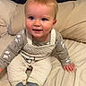 Sutton is registered to the contest to win money with this photo: baby, child, infant, bed, pajamas, overalls, socks, blue_eyes, hair, cute, smiling, indoors, cozy, blanket, fabric, person, sitting, sleepwear, face, happy