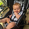 baby, child, stroller, outdoor, smile, blue_eyes, onesie, mickey_mouse, cute, happy, playful, seatbelt, hand, legs, sunlight, black_stroller, mesh_canopy, concrete_ground, infant, person