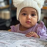 baby, cafe, child, clothing, curious, cute, face, food_menu, hand, hat, indoor, knit, menu, person, pom_poms, portrait, purple_shirt, soft_light, table, young