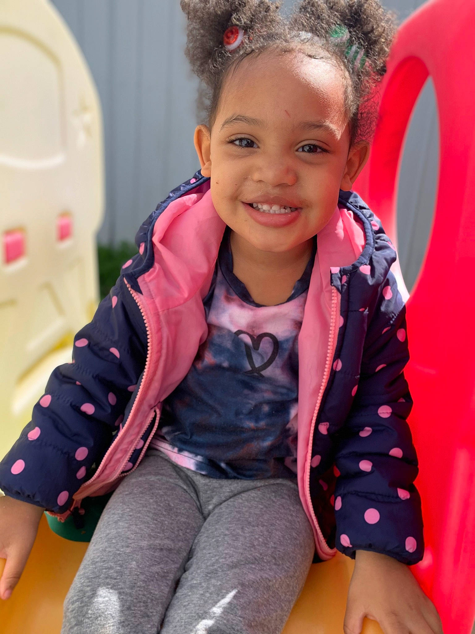 Italy is registered to the contest to win money with this photo: baby_toddler_clothing, chair, child, comfort, face, facial_expression, fun, hairstyle, happy, joy, leg, leisure, magenta, neck, person, pink, red, skin, sleeve, smile