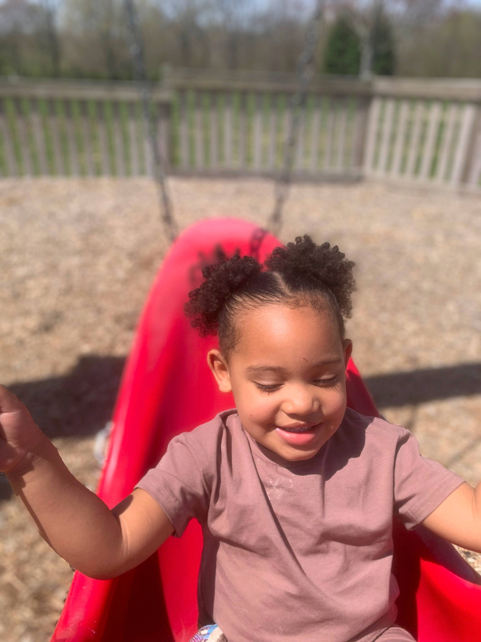 Italy is registered to the contest to win money with this photo: baby_toddler_clothing, child, eye, facial_expression, fence, fun, grass, happy, joy, leisure, magenta, outdoor_play_equipment, people_in_nature, person, play, playground, recreation, sitting, skin, smile