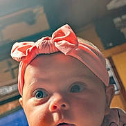 Grace is registered to the contest to win money with this photo: baby, infant, face, headband, pink, bow, child, closeup, curious, eyes, cheeks, indoor, soft_lighting, portrait, cute, expression, young, wearing, clothing, headwear