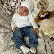 Truth is registered to the contest to win money with this photo: baby, infant, sleeping, newborn, two_months_sign, hat, jeans, socks, blanket, plush_lion, fur_blanket, cozy, portrait, wooden_sign, soft_texture, nap, cute, hands, face, smile_less