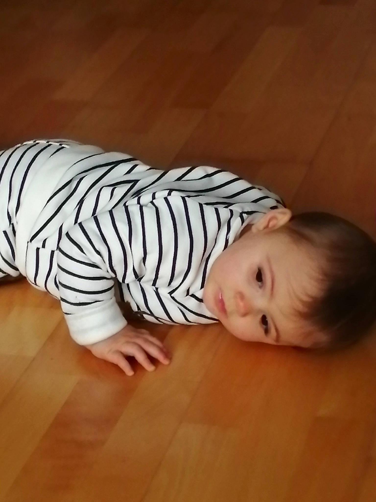 Alba participe au concours pour gagner de l'argent avec cette photo : baby, baby_toddler_clothing, cheek, comfort, finger, floor, flooring, foot, fun, happy, hardwood, hat, knee, pattern, person, sitting, sleeve, t_shirt, toddler, wood