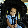 toddler, child, car_seat, car_interior, seatbelt, blue_clothing, smile, sitting, baby, safety, vehicle, window, daylight, cute, young_child, portrait, indoors, seat, face, person