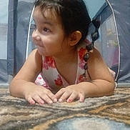 Reyna joined the competition — help win amazing prizes! child, girl, braid, smile, carpet, indoor, playpen, curious, cute, young, portrait, patterned_carpet, happy, person, toddler, clothing, pink, flower_pattern, hair, fingers