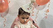 Penelope is registered to the contest to win money with this photo: baby, birthday, birthday_hat, balloons, cake, smash_cake, fruit, strawberries, blueberries, raspberries, high_chair, seated, child, infant, party, celebration, pink, indoor, ribbons, smiling