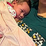 Billie is registered to the contest to win money with this photo: baby, newborn, blanket, person, face, clothing, leopard_print, green_shirt, skin, head, resting, cuddle, indoor, soft_texture, closeup, portrait, infant, human, sleepy, calm