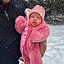 baby, infant, child, winter_clothing, pink_suit, knit_hat, pacifier_clip, snow, snowfall, adult_hand, outdoor, cold_weather, warm_clothing, face, person, coat, jacket, fuzzy_texture, nature, tree