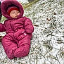 Paisley is registered to the contest to win money with this photo: baby, child, snow, winter_clothing, pink_snowsuit, red_hat, grass, outdoor, cold_weather, sitting, footwear, adult_leg, curious_expression, winter, frozen_ground, nature, person, clothing, cold, season