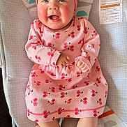 Ailany is registered to the contest to win money with this photo: baby, infant, smiling, pink_dress, headband, baby_seat, colorful, happy, cute, child, floral_pattern, indoors, cheerful, monkey_design, sun_design, clothing, feet, portrait, sitting, young_child