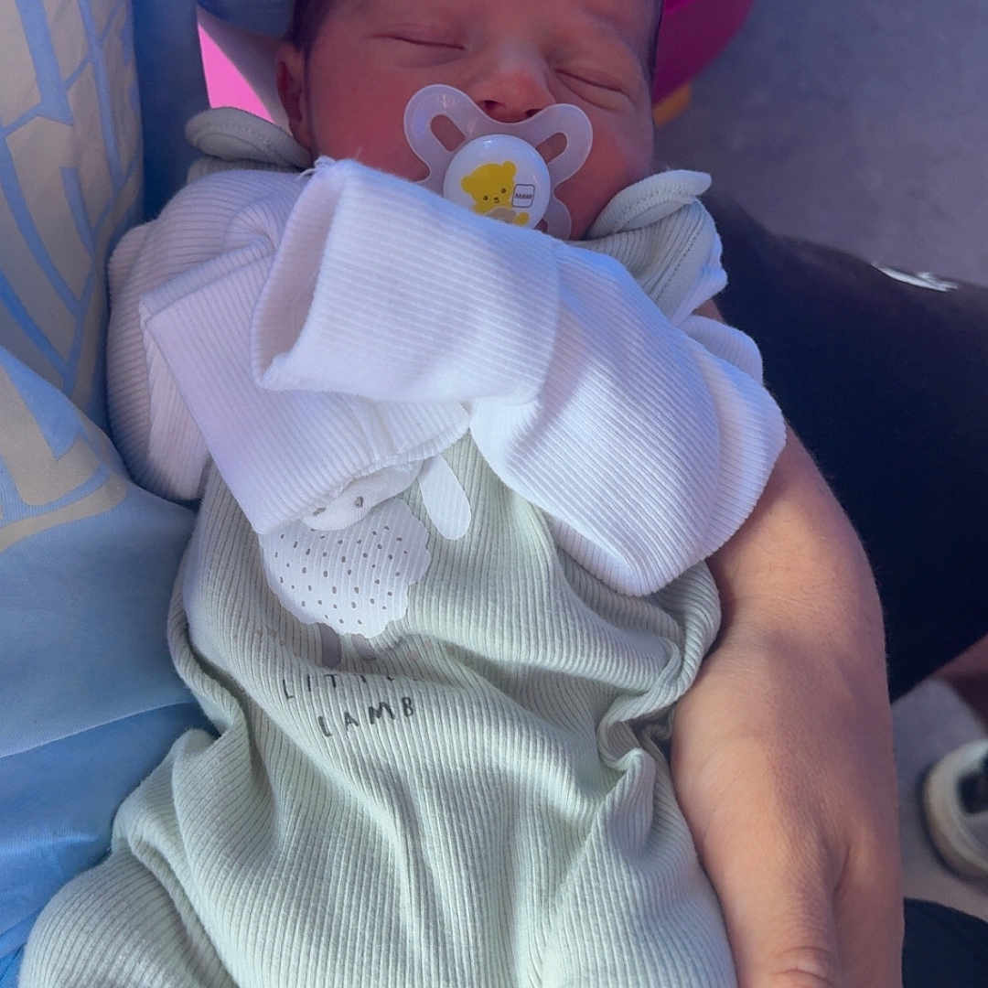 Noah is registered to the contest to win money with this photo: baby, bed, blanket, bodypart, clothing, couch, cushion, face, finger, furniture, hand, hat, head, homedecor, newborn, pants, person, photography, portrait, sleeping