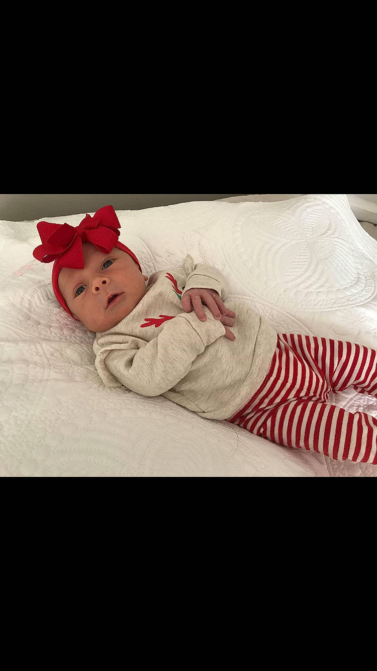 Lily Kate is registered to the contest to win money with this photo: arm, baby, child, ear, fashion_accessory, headgear, model, pajamas, person, photo_shoot, photography, plant, red, skin, sleeve, toddler