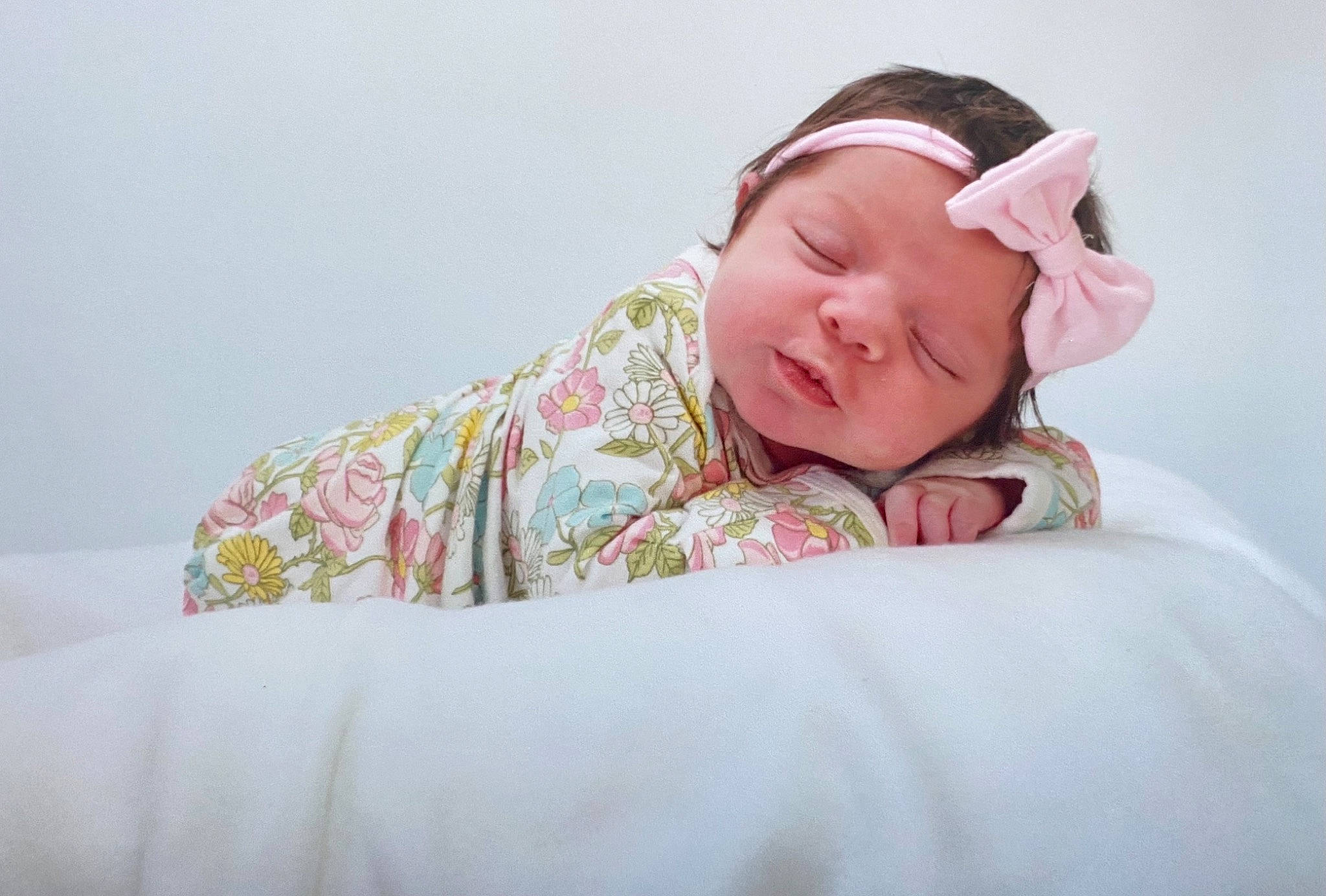 Liliana is registered to the contest to win money with this photo: arm, baby, baby_sleeping, baby_toddler_clothing, bedding, cheek, collar, comfort, eye, happy, headpiece, headwear, human_body, linens, lip, neck, pattern, peach, person, sitting