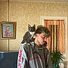 Anakin participe au concours pour gagner de l'argent avec cette photo : beige_wall, casual_clothing, curious, curtain, feline, gray_hoodie, hair, home_decor, indoor, kitten, pet, plant_pot, portrait, portrait_photo, potted_plant, shoulder_perch, smile, television, tinsel, young_man